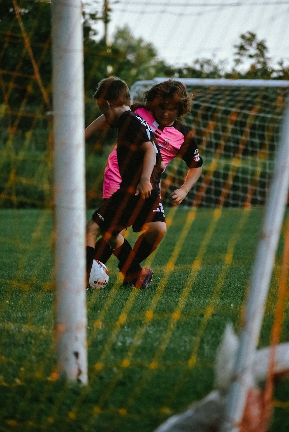 Two children playing soccer on a grassy field.