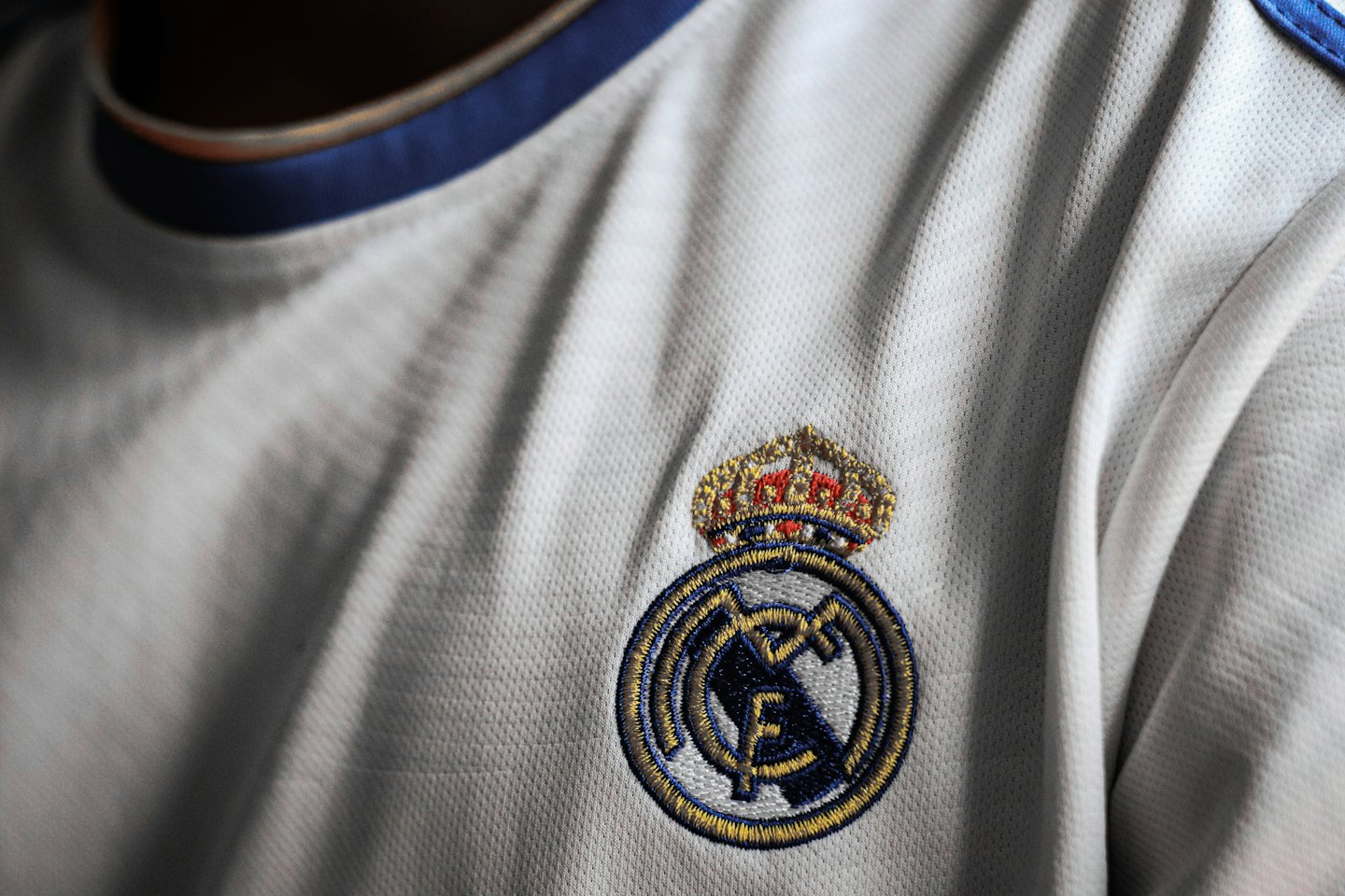Embroidered club emblem on a textured sports jersey.