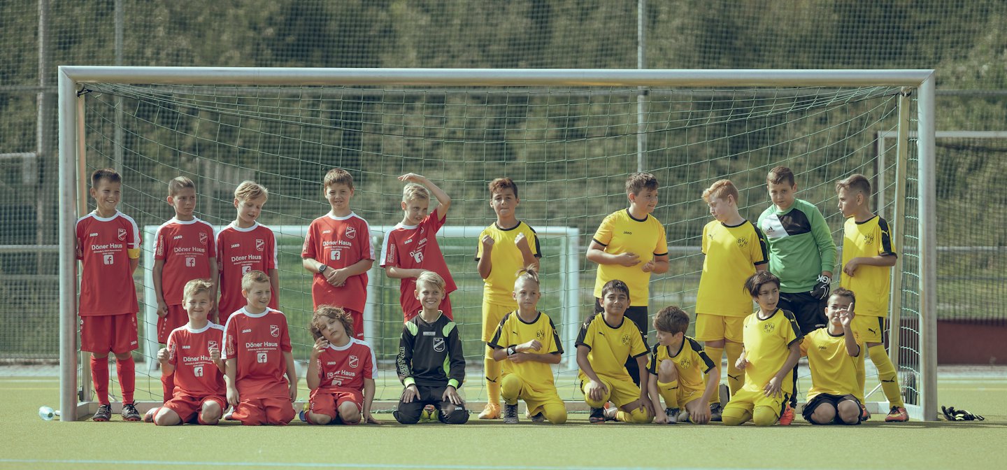 Youth soccer team in red and yellow uniforms posing on the field.