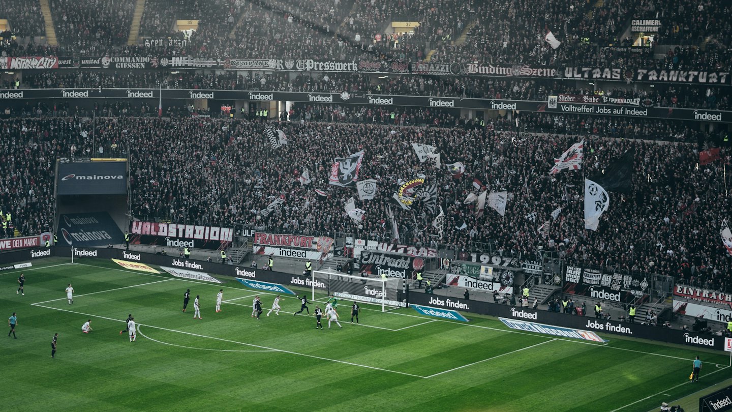 Soccer players in white and black uniforms play near the goal.